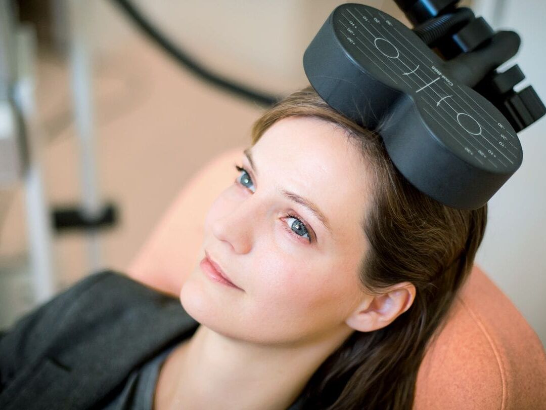 Woman seated with a TMS coil positioned on her head