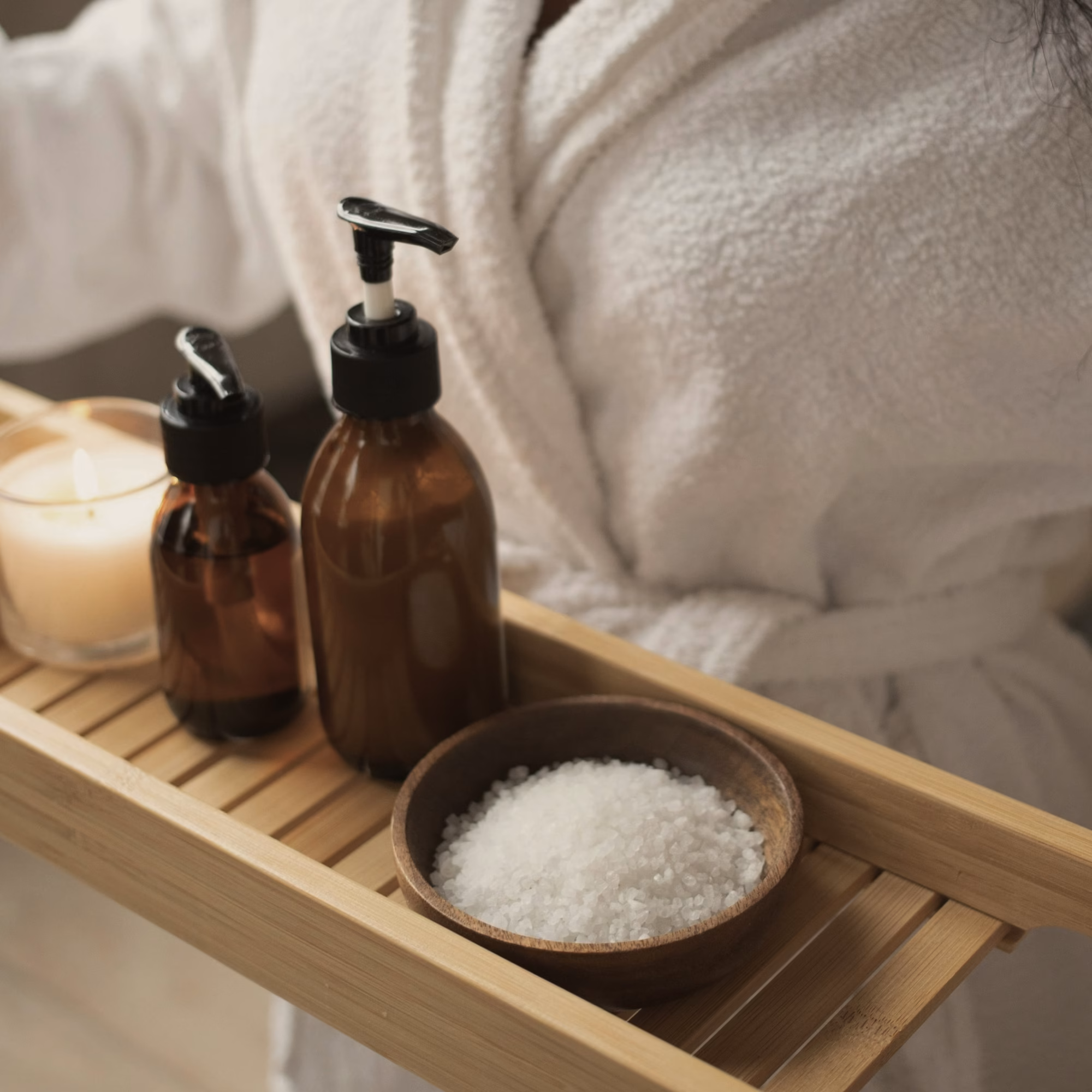 Bathrobe, candle and bath salts on a wooden spa tray